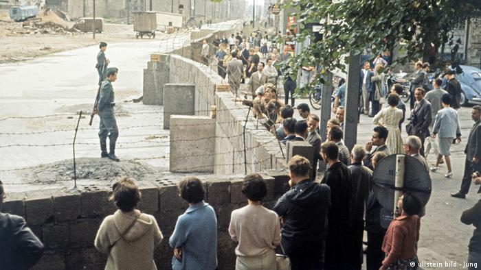 Menschen schauen über die Berliner Mauer, dahinter stehen Soldaten (ullstein bild - Jung)