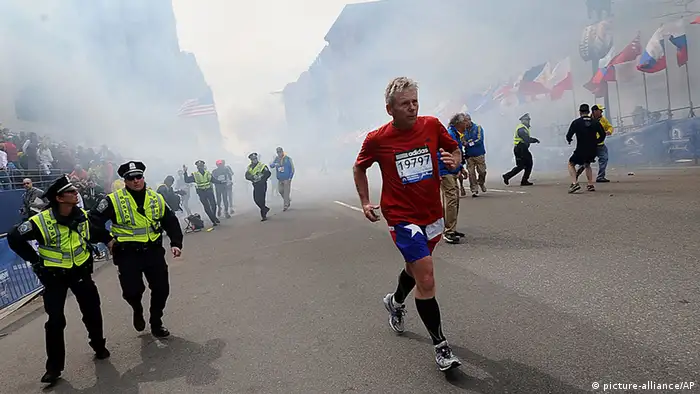 A Boston Marathon competitor and Boston police run from the area of an explosion near the finish line in Boston, Monday, April 15, 2013. (AP Photo/MetroWest Daily News, Ken McGagh) MANDATORY CREDIT