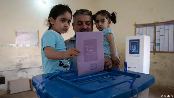 A man holds his daughters as he casts his ballot during Iraq's provincial elections, April 2013. (Photo: Atef Hassan)