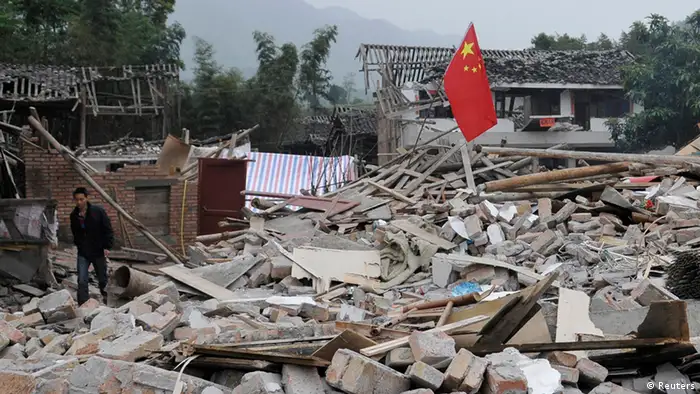 A man walks past a Chinese national flag planted on debris on the second day after an earthquake hit Longmen township of Lushan county, Sichuan province April 21, 2013. Rescuers struggled to reach a remote corner of southwestern China on Sunday as the toll of the dead and missing from the country's worst earthquake in three years climbed to 203 with more than 11,000 injured. The 6.6 magnitude quake struck in Lushan county, near the city of Ya'an in the southwestern province of Sichuan, close to where a devastating 7.9 temblor hit in May 2008 killing some 70,000. REUTERS/Stringer (CHINA - Tags: DISASTER) CHINA OUT. NO COMMERCIAL OR EDITORIAL SALES IN CHINA