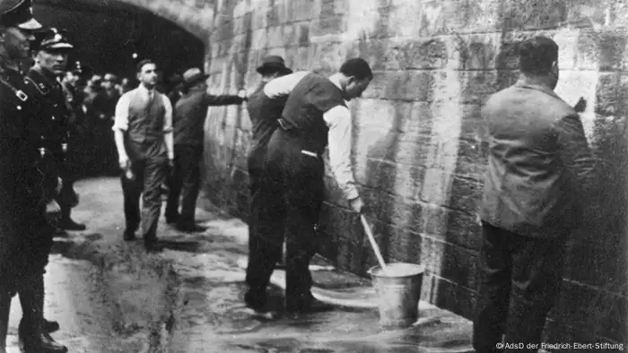 SPD-Politiker werden 1933 unter Aufsicht der SA gezwungen, Wandparolen zu entfernen, Foto: © AdsD der Friedrich-Ebert-Stiftung. 