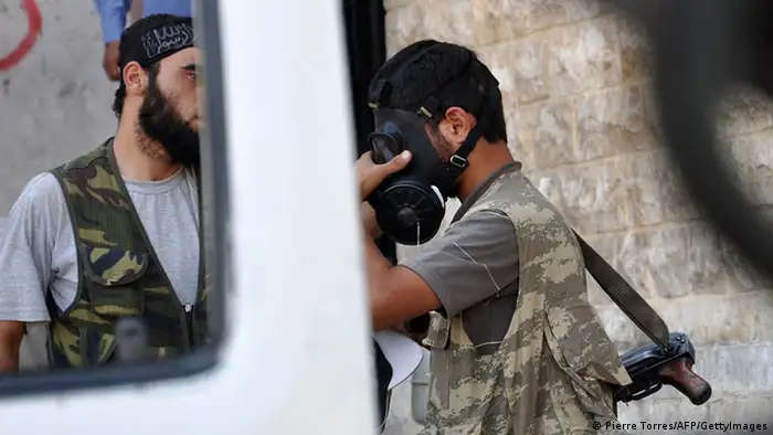A Syrian opposition fighter tries a gasmask in the northern city of Aleppo on July 25, 2012. Battles raged through the night in several districts of Syria's second largest city to which the regime had rushed reinforcement, after rebels launched an all-out assault for control of the country's commercial hub on July 20. Arabic graffiti on the police station's entrance reads Assad's Syria. AFP PHOTO / PIERRE TORRES (Photo credit should read Pierre Torres/AFP/GettyImages)