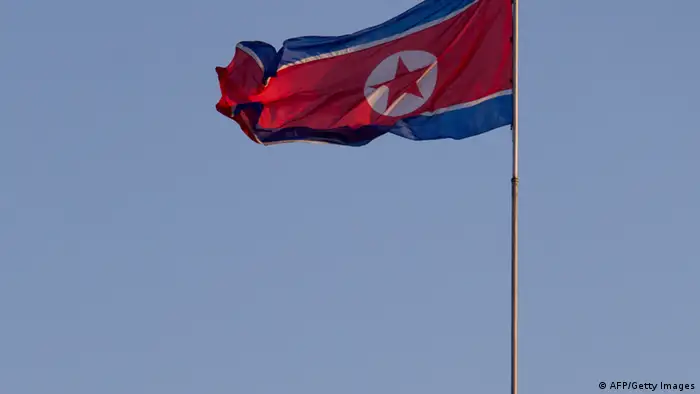 A soldier stands beneath a North Korean flag prior to celebrations to mark the 100th birth anniversary of the country's founding leader Kim Il-Sung, in Pyongyang on April 16, 2012. The commemorations came just three days after a satellite launch timed to mark the centenary fizzled out embarrassingly when the rocket apparently exploded within minutes of blastoff and plunged into the sea. AFP PHOTO / Ed Jones (Photo credit should read Ed Jones/AFP/Getty Images)