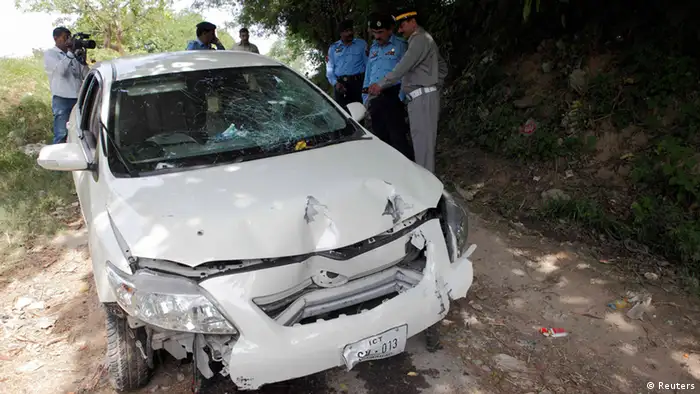 Security officials inspect the damaged car, which prosecutor Chaudhry Zulfikar was travelling in, when he came under attack by unidentified gunmen, in Islamabad May 3, 2013. Zulfikar, the prosecutor investigating the 2007 assassination of former Pakistani Prime Minister Benazir Bhutto, one of the most shocking events in Pakistan's turbulent history, was shot dead on Friday, police sources said. Gunmen on a motorcycle pumped 12 bullets into Zulfikar as he left his home in Islamabad, the sources said. REUTERS/Mian Khursheed (PAKISTAN - Tags: POLITICS CIVIL UNREST CRIME LAW)