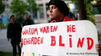 A protester holds a placard in front of a courthouse, where the trial against Beate Zschaepe, a member of the neo-Nazi group National Socialist Underground (NSU), will start later today, in Munich May 6, 2013. The surviving member of NSU blamed for a series of racist murders that scandalised Germany and shamed its authorities goes on trial on Monday in one of the most anticipated court cases in recent German history. The trial in Munich will focus on 38-year-old Zschaepe, who is charged with complicity in the murder of eight Turks, a Greek and a policewoman between 2000-2007, as well as two bombings in immigrant areas of Cologne, and 15 bank robberies. Four others charged with assisting the NSU will sit with Zschaepe on the bench. The placard reads, Why the authorities have been blind. REUTERS/Kai Pfaffenbach (GERMANY - Tags: CIVIL UNREST CRIME LAW POLITICS)