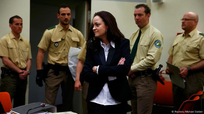 Beate Zschäpe im Gerichtssaal, bewacht von vier Polizisten.