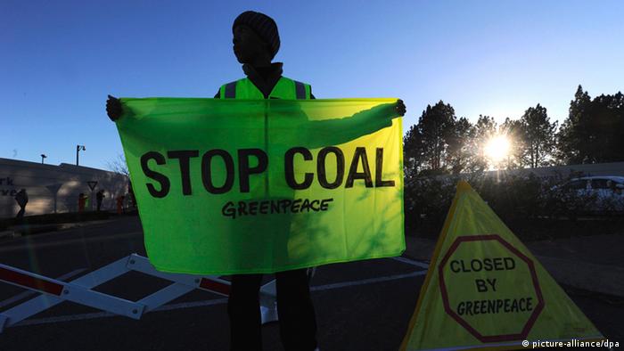 Greenpeace Africa activist holds a banner with the words STOP COAL