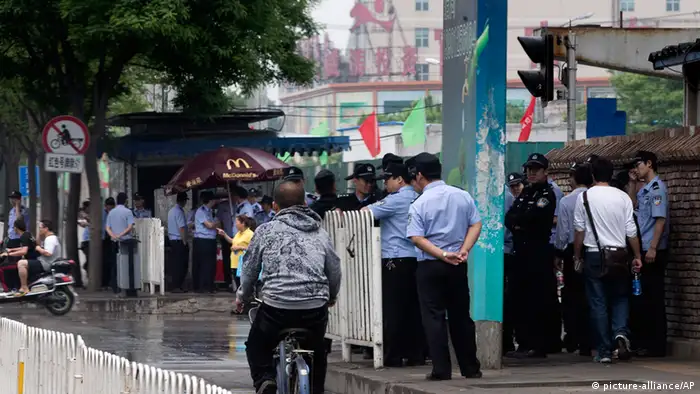 Chinese policemen stand guard on a pavement near a clothing wholesale mall where a woman fell to her death on May 3, in Beijing Thursday, May 9, 2013. With anti-riot vans and helmeted paramilitary forces, police in China's capital smothered a southern district for a second day Thursday after a protest by hundreds of migrant workers, underscoring the authorities sensitivity over unrest driven by anger over social inequality. (AP Photo/Andy Wong)