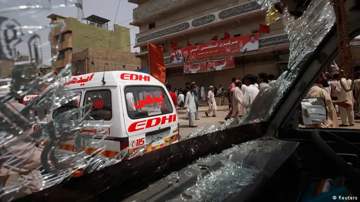 Security officials and residents are seen through the shattered windscreen of a damaged vehicle at the site of a bomb attack in Karachi May 11, 2013. A bomb attack on the office of the Awami National Party (ANP) in the commercial capital, Karachi, killed 11 people and wounded 35. At least two were wounded in a pair of blasts that followed and media reported gunfire in the city. REUTERS/Athar Hussain (PAKISTAN - Tags: POLITICS ELECTIONS CIVIL UNREST CRIME LAW)