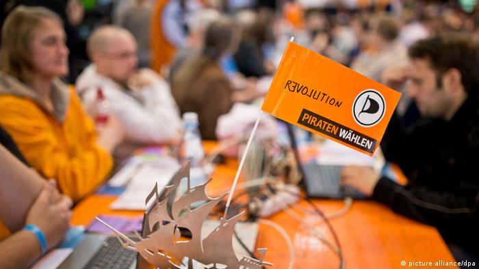 Eine Fahne mit dem Logo der Piratenpartei und der Aufschrift Revolution steht am 12.05.2013 beim Bundesparteitag der Piraten in Neumarkt in der Oberpfalz (Bayern) auf einem Tisch. Foto: Daniel Karmann/dpa +++(c) dpa - Bildfunk+++