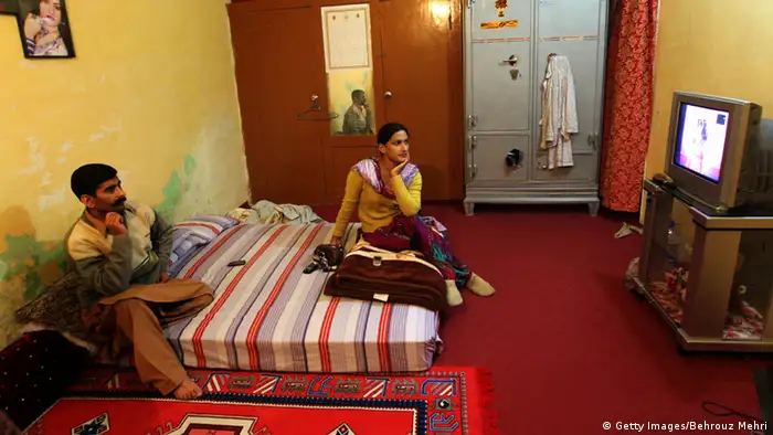 Pakistani eunuch Saba and her boyfriend Nasser (L) watch TV in her room in Rawalpindi on January 18, 2010. On the bottom rungs of Pakistan's social ladder, the eunuchs or Hijras scrape out a hard existence. Cultural descendants of the court eunuchs of the Mughal Empire (1526-1858), the eunuchs are often shunned by their families and forced to make a living by dancing, begging or as prostitutes (Foto: AFP PHOTO/BEHROUZ MEHRI).