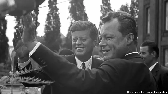 Präsident Kennedy (l) und Berlins Regierender Bürgermeister Willy Brandt (r) winken vor dem Rathaus Schöneberg der versammelten Menge zu - Foto: dpa