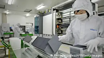 TO GO WITH UN-climate-warming-China-solar,FOCUS by D'Arcy Doran This picture taken on November 28, 2009 shows a masked worker in a lab coat sorting silicon wafers at the manufacturing centre of solar cell maker Trina Solar in Changzhou. China has suddenly become the world's biggest solar cell manufacturing centre, thanks to companies like New York Stock Exchange-listed Trina, which have ramped up capacity, hoping benefit from world leaders' pledges at the December 7-18 Copenhagen summit. AFP PHOTO / PHILIPPE LOPEZ (Photo credit should read PHILIPPE LOPEZ/AFP/Getty Images)