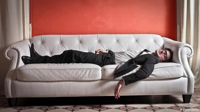 Ein Mann im Anzug schläft auf einem Sofa