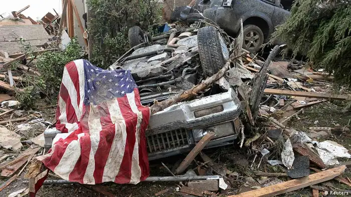 An American flag lies on top of an overturned car after a tornado struck Moore, Oklahoma, May 20, 2013. A 2-mile-wide (3-km-wide) tornado tore through the Oklahoma City suburb of Moore on Monday, killing at least 51 people while destroying entire tracts of homes, piling cars atop one another, and trapping two dozen school children beneath rubble. REUTERS/Gene Blevins (UNITED STATES - Tags: ENVIRONMENT DISASTER)