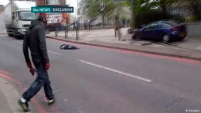 AATTENTION EDITORS - VISUAL COVERAGE OF SCENES OF INJURY OR DEATH A man with bloodied hands and knives walks across a street past the body of a man in a still image from amateur video that shows the immediate aftermath of an attack in which a man was killed in southeast London May 22, 2013. A man was hacked to death in a street near an army barracks in London on Wednesday in what Prime Minister David Cameron said appeared to be a politically motivated attack. MANDATORY CREDIT to ITV News. REUTERS/ITV News via Reuters TV (BRITAIN - Tags: CRIME LAW MILITARY CIVIL UNREST) USE FOR 48 HOURS ONLY. NO SALES. NO ARCHIVES. FOR EDITORIAL USE ONLY. NOT FOR SALE FOR MARKETING OR ADVERTISING CAMPAIGNS. NO ONLINE USE. NOT FOR SALE FOR INTERNET DISPLAY. MANDATORY CREDIT. TEMPLATE OUT