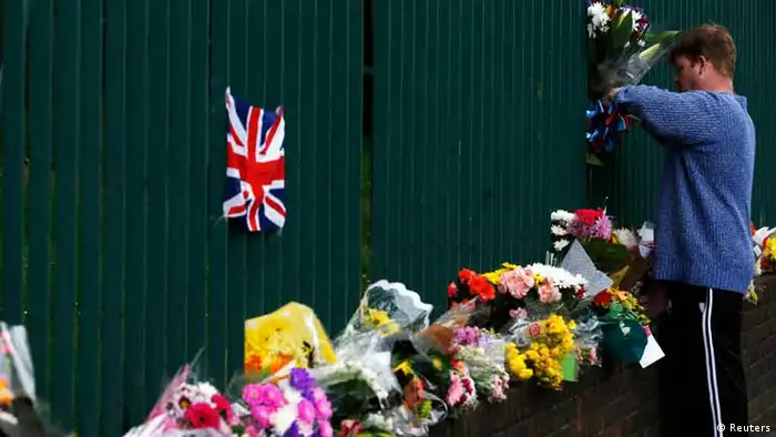 A man leaves a floral tribute for Drummer Lee Rigby, of the British Army's 2nd Battalion The Royal Regiment of Fusiliers, at a security fence outside army barracks near the scene of his killing in Woolwich, southeast London May 24, 2013. Police investigating the murder of the soldier on a busy London street are looking into whether the two suspected killers, British men of Nigerian descent, were part of a wider conspiracy. REUTERS/Luke MacGregor (BRITAIN - Tags: CRIME LAW MILITARY)