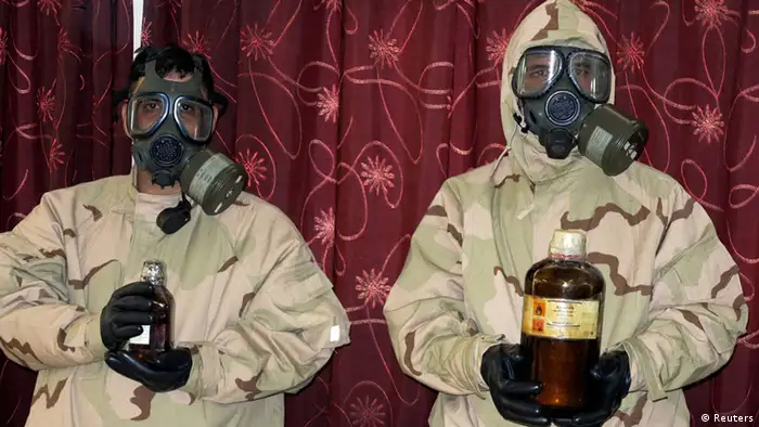 Soldiers wearing gas masks hold bottles containing chemical materials during a news conference at the Defence Ministry in Baghdad June 1, 2013. The materials were confiscated from four men who have been arrested, and are accused of planning to make chemical weapons like nerve and mustard gas, according to the ministry. REUTERS/Stringer (IRAQ - Tags: CIVIL UNREST CRIME LAW)