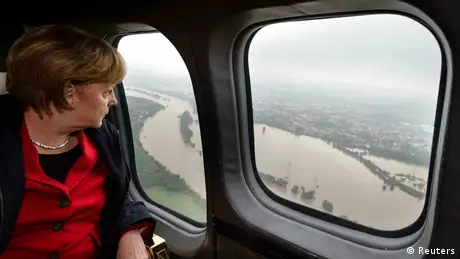 Chancellor Angela Merkel looks through the window of an airplane or helicopter toward floodwaters on the ground
(Photo: Steffen Kugler/Reuters)