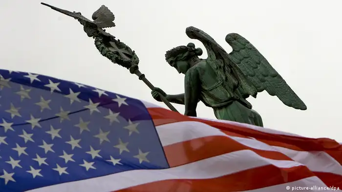 Vor der Quadriga-Figur des Brandenburger Tors in Berlin weht eine US-Fahne - Foto: Arno Burgi (dpa)