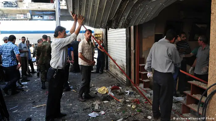 In this photo released by the Syrian official news agency SANA, Syrians inspect a damaged shop at a scene of two explosions in the central district of Marjeh, Damascus, Syria, Tuesday, June 11, 2013. Two explosions hit a central Damascus square Tuesday, killing and wounding dozens of people, activists and the state media reported. State TV said the blasts were caused by suicide bombers, while activists said they were bombs planted there in advance. (AP Photo/SANA) pixel AP PROVIDES ACCESS TO THIS PUBLICLY DISTRIBUTED HANDOUT BY SANA PHOTO TO BE USED ONLY TO ILLUSTRATE NEWS REPORTING OR COMMENTARY ON THE FACTS OR EVENTS DEPICTED IN THIS IMAGE.