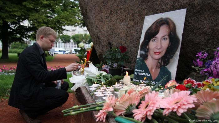 Photo with a portrait of Natalia Estemirova, in front of which there are flowers and candles in memory of her