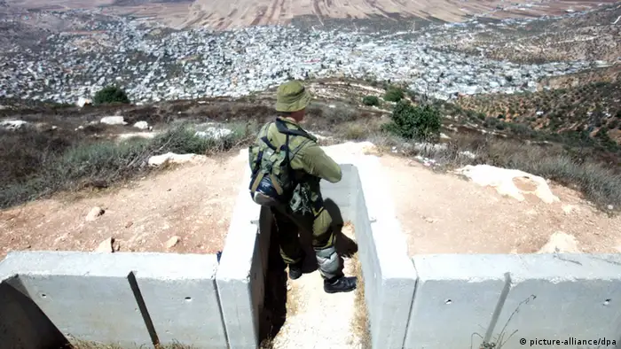 epa02858902 An Israeli soldier stands in a cement trench as he guards the 'outpost' Jewish settlement of Itamar in thenorthern West Bank, on 07 August 2011. The settlement on the top of a hill overlooks the Palestinian village of Beit Rurik near the city of Nablus, has about 1,032 residents. EPA/ABIR SULTAN