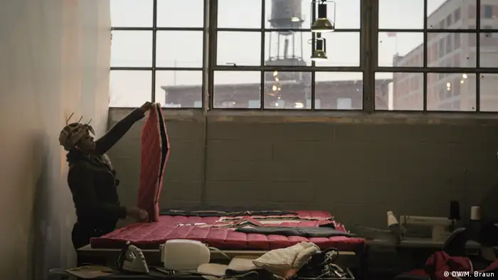 In einer großen Fabrikhalle fertigt eine Näherin einer rote gesteppte Decke für Obdachlose. (Foto: DW/M. Braun) 