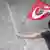 Демонстрант держит в руке турецкий флаг и уворачивается от струи воды из водомета