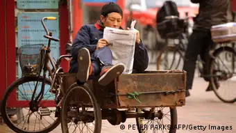 A man reads a newspaper whilst sitting in his tricycle on a street in Shanghai on January 9, 2013. The Southern Weekly, a popular liberal newspaper based in Guangzhou and at the centre of rare public protests about government censorship will publish as usual on January 10, a senior reporter said, following reports of a deal to end a censorship row after hundreds of people demanded greater press freedom after an article urging reforms to uphold people's rights was censored by an official. AFP PHOTO/Peter PARKS (Photo credit should read PETER PARKS/AFP/Getty Images)