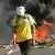 This June 19, 2013 photo, a masked protester walks away from a burning barricade near the Castelao stadium in Fortaleza, Brazil.(AP Photo/Andre Penner, File)
