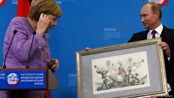 Russia's President Vladimir Putin (R) presents a historical lithograph to Germany's Chancellor Angela Merkel during a news conference after their meeting at the St. Petersburg International Economic Forum in St. Petersburg, June 21, 2013. REUTERS/Alexander Demianchuk (RUSSIA - Tags: BUSINESS POLITICS)
