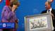 Russia's President Vladimir Putin (R) presents a historical lithograph to Germany's Chancellor Angela Merkel during a news conference after their meeting at the St. Petersburg International Economic Forum in St. Petersburg, June 21, 2013. REUTERS/Alexander Demianchuk (RUSSIA - Tags: BUSINESS POLITICS) Russia's President Vladimir Putin (R) presents a historical lithograph to Germany's Chancellor Angela Merkel during a news conference after their meeting at the St. Petersburg International Economic Forum in St. Petersburg, June 21, 2013. REUTERS/Alexander Demianchuk (RUSSIA - Tags: BUSINESS POLITICS)