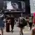 People cross a street in front of a monitor showing file footage of Edward Snowden, a former contractor for the U.S. National Security Agency (NSA), with a news tag (L) saying he has left Hong Kong, outside a shopping mall in Hong Kong June 23, 2013. (Photo: REUTERS/Bobby Yip)