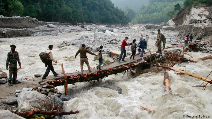 Indian army personnel help stranded people cross a flooded river after heavy rains in the Himalayan state of Uttarakhand June 23, 2013. Flash floods and landslides unleashed by early monsoon rains have killed at least 560 people in Uttarakhand and left tens of thousands missing, officials said on Saturday, with the death toll expected to rise significantly. Picture taken June 23, 2013. REUTERS/Stringer (INDIA - Tags: DISASTER ENVIRONMENT MILITARY TPX IMAGES OF THE DAY)
