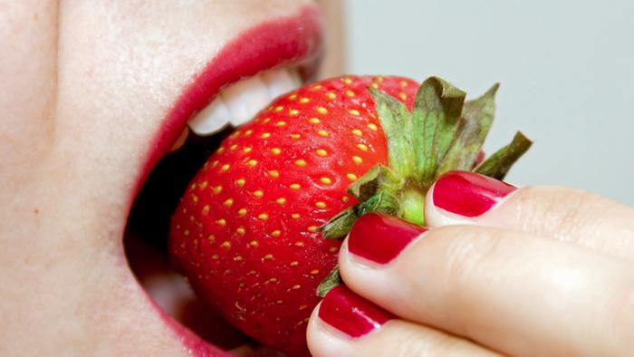 A woman biting into a strawberry. (Photo: DW Projekt Zukunft Erdbeeren)