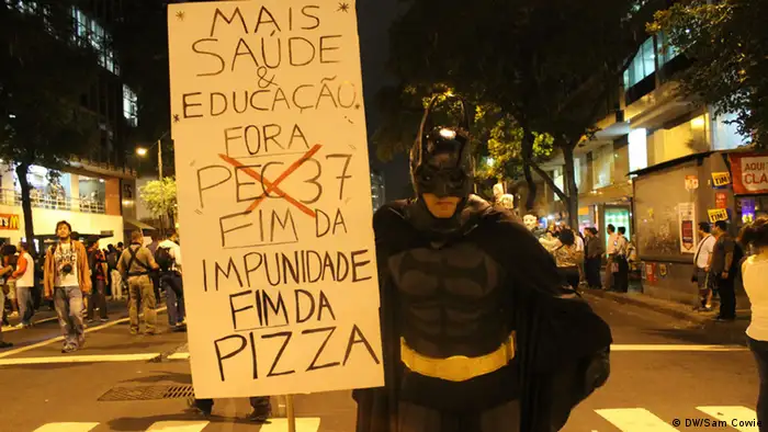Ein Mann im Batman-Dress hält ein Plakat hoch.