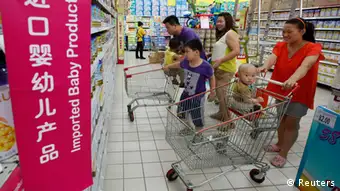 A family looks at foreign imported milk powder products at a supermarket in Beijing July 3, 2013. The decision by China's top economic planner to investigate five leading foreign infant milk companies for suspected antitrust violations may be part of a broader plan to boost consumption of the local product, analysts said on Wednesday. Mothers turned away from Chinese milk powder in 2008 when infant formula tainted with the industrial compound melamine killed at least six babies and made thousands sick with kidney stones. REUTERS/Kim Kyung-Hoon (CHINA - Tags: BUSINESS FOOD HEALTH)