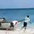 Workers for NGO Nature Seychelles move a boat on Cousin Island