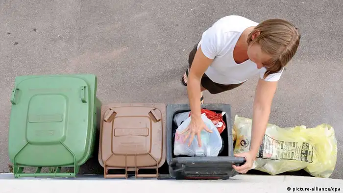 Eine Frau wirft Müll in eine graue Tonne (Foto: dpa)