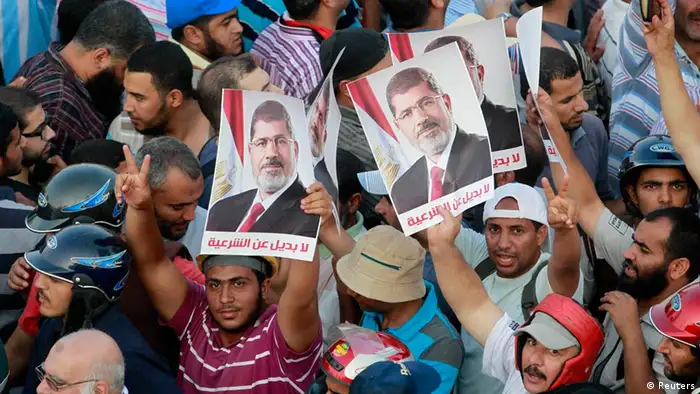 Supporters of deposed Egyptian President Mohamed Mursi hold posters during a protest outside Rabaa Adawiya mosque in Cairo July 9, 2013. Egypt's interim President Adli Mansour on Tuesday named liberal economist and former finance minister Hazem el-Beblawi as prime minister in a transitional government, as the authorities sought to steer the country to new parliamentary and presidential elections. The posters read, No substitute for the legitimacy. REUTERS/Louafi Larbi (EGYPT - Tags: POLITICS CIVIL UNREST)