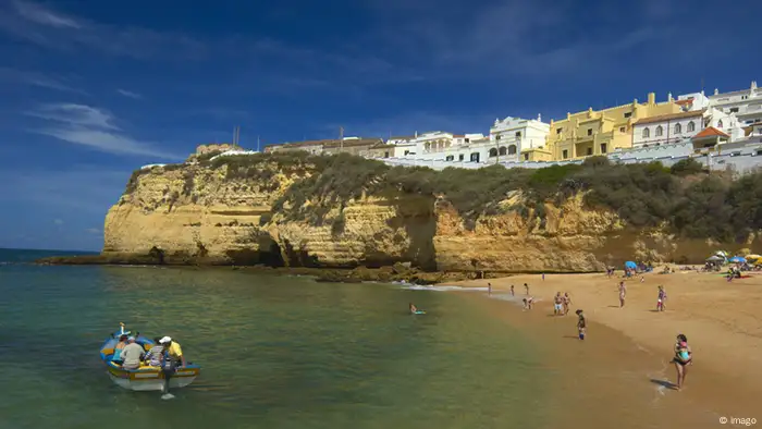 Ein Boot und Badenden am Algarve-Strand in Portugal 