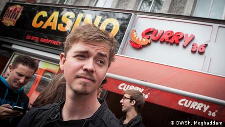 Rapper Kurt steht vor einem Currywurst-Laden in Berlin.