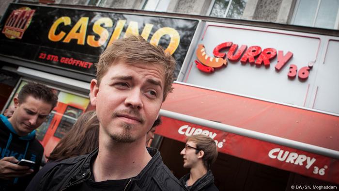 Rapper Kurt steht vor einem Currywurst-Laden in Berlin.