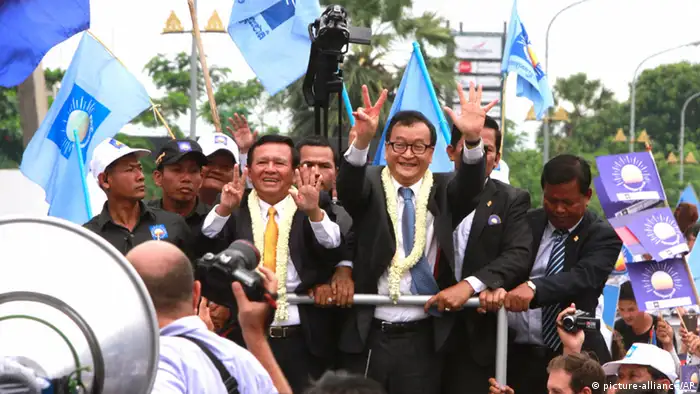 Sam Rainsy, center right, president of Cambodia National Rescue Party (CNRP) greets his supporters together with his party's Vice President Kem Sokha, center left, on his arrival at Phnom Penh International Airport in Phnom Penh, Cambodia, Friday, July 19, 2013. Thousands of cheering supporters greeted Cambodian opposition leader Sam Rainsy as he returned from self-imposed exile Friday to spearhead his party's election campaign against well-entrenched Prime Minister Hun Sen. (AP Photo/Heng Sinith)