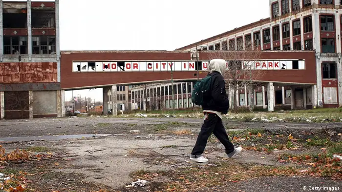 Eine leere Fabrikanlage mit Verbindungsgängen zwischen den riesigen Fabrikhallen lassen erkennen, dass die Automobilindustrie in Detroit eins boomte. Die Anlage ist verlassen, Bäume wachsen in den Gebäuden, nur ein junger Mann läuft durch das Bild (Foto: Spencer Platt/Getty Images)