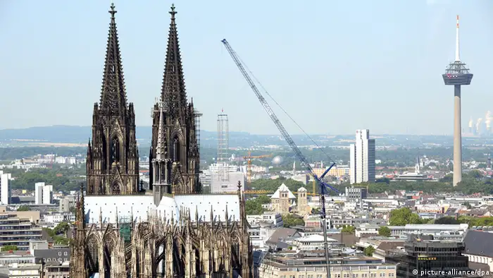 Ein Kran hebt am 22.07.2013 in Köln ein Baugerüst vom Dom ab. Foto: Federico Gambarini/dpa 