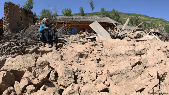 Eine Frau sitzt auf den Trümmern ihres zusammengestürzten Hauses - nach Erdbeben in China 2013