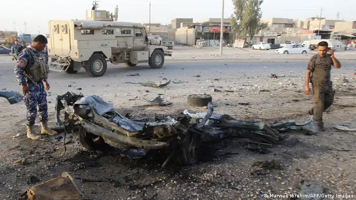 An Iraqi soldier (L) inspects the wreck of a car bomb after it exploded in the military zone of the northern Iraqi city of Kirkuk on July 11, 2013. Militants killed 25 Iraqi security forces members in a wave of attacks and 15 people died in other attacks, including 10 in twin bombings targeting mourners, officials said. AFP PHOTO MARWAN IBRAHIM (Photo credit should read MARWAN IBRAHIM/AFP/Getty Images)