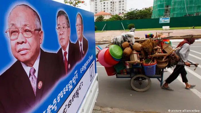 epa03797956 A Cambodian man pulls his cart, which is loaded with baskets and other household goods to sell, passing portraits of Cambodian People's Party leaders Chea Sim (L), Prime Minister Hun Sen (2-L), and President of the National Assembly Heng Samrin (3-L), in Phnom Penh, Cambodia, 23 July 2013. Cambodia's fifth national assembly elections are scheduled on 28 July. EPA/MAK REMISSA +++(c) dpa - Bildfunk+++